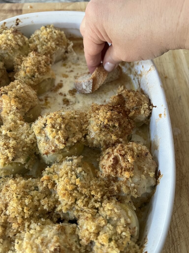 Soaking up some sauce on the bottom of the baking dish from the artichoke bottoms stuffed with crabmeat with a piece of bread.