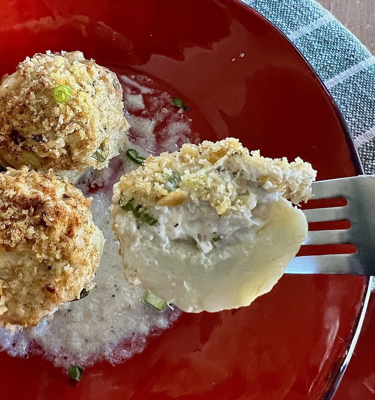 Close up of half of one artichoke bottom stuffed with crabmeat o fork.
