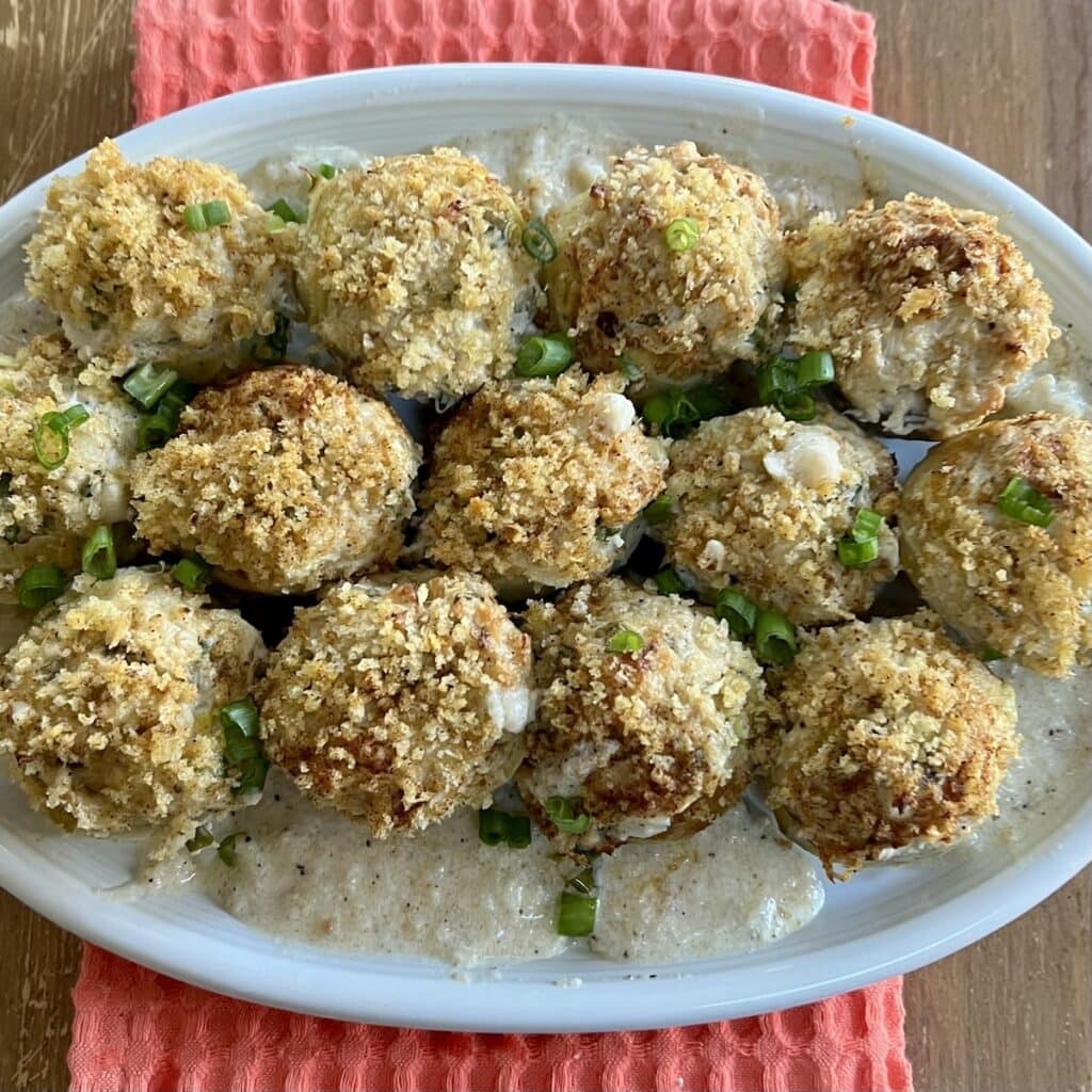 Crab Stuffed Artichoke Bottoms on white serving platter over decorative towel.
