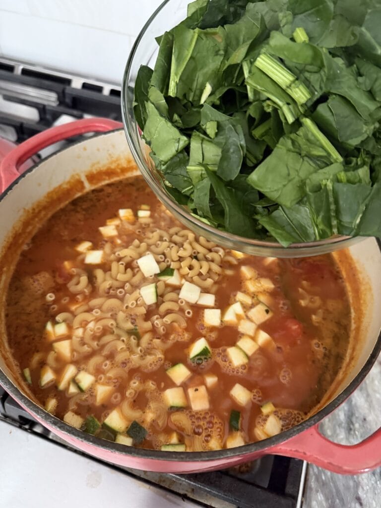 Adding spinach to soup mixture.