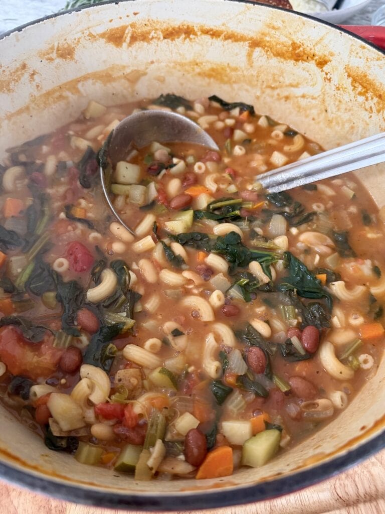 Ladle in pot of traditional minestrone soup.