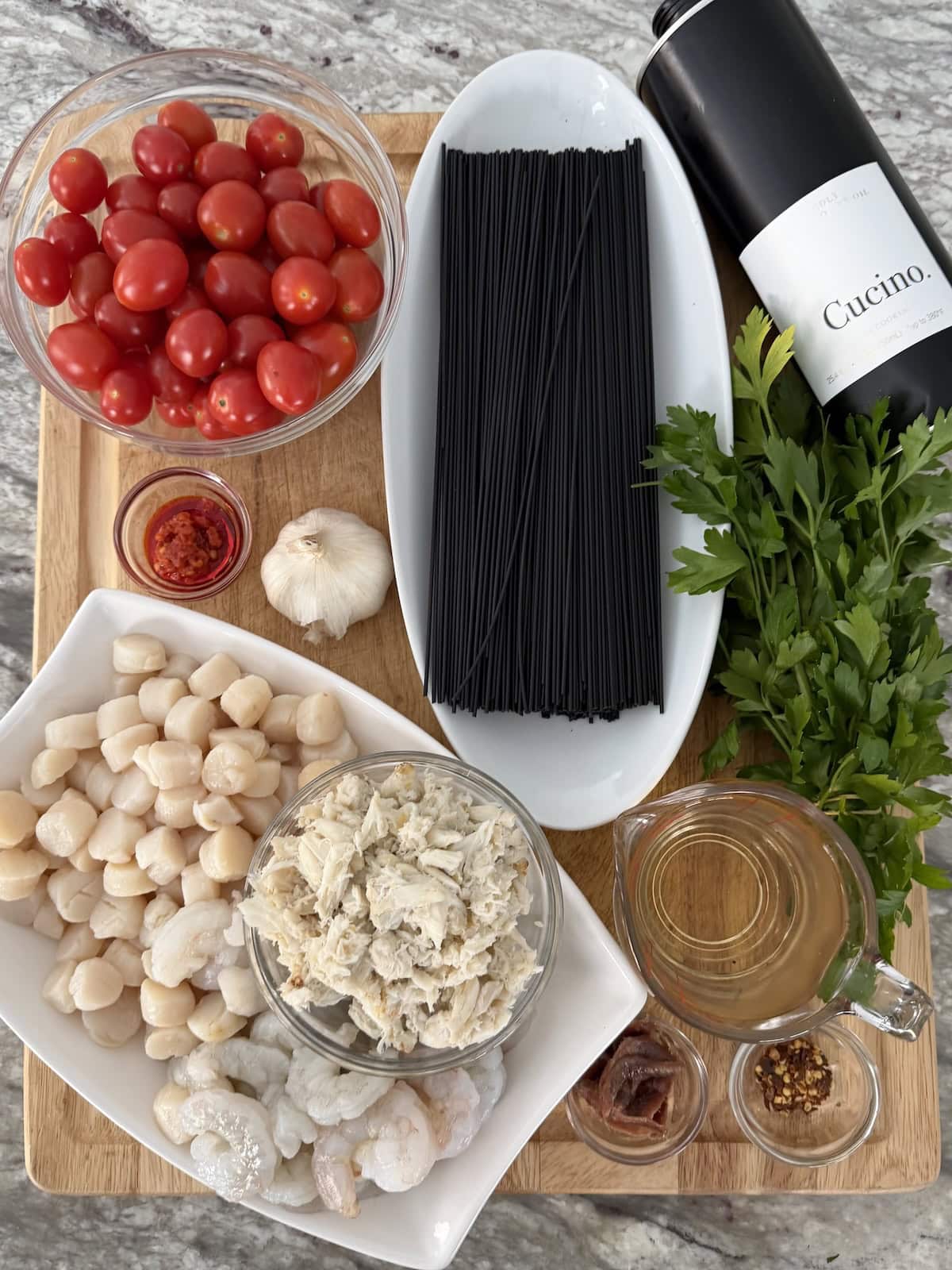 All ingredients for Spaghetti Allo Scoglio with cuttlefish ink pasta on cutting board.