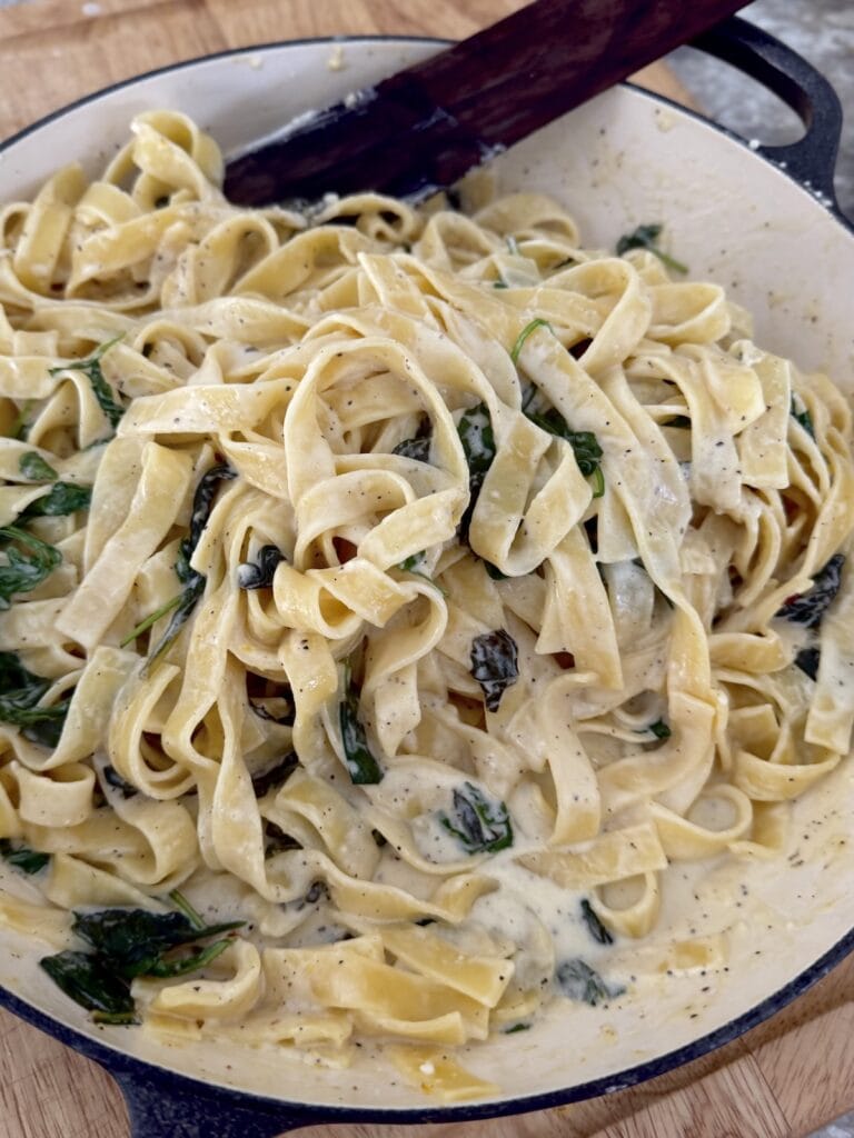 Finished lemon pasta in pan with wooden utensil.