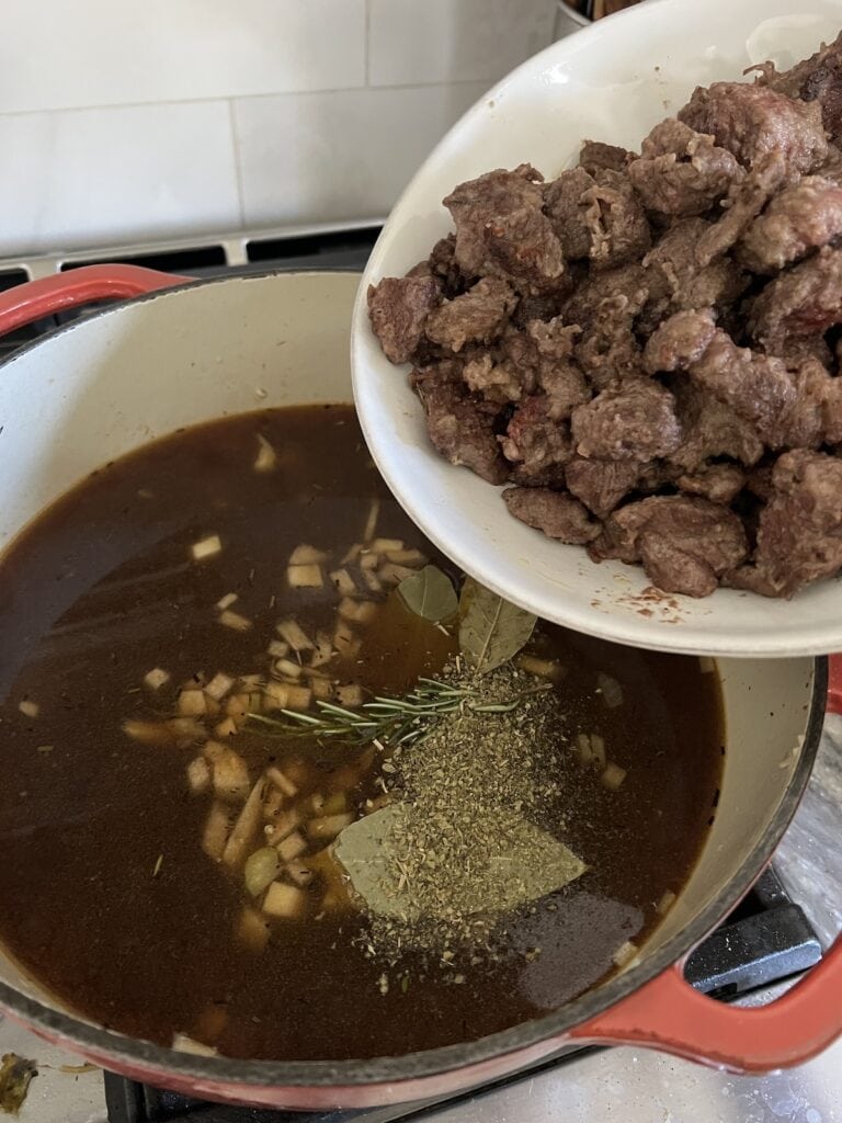 Adding browned meat to pot.