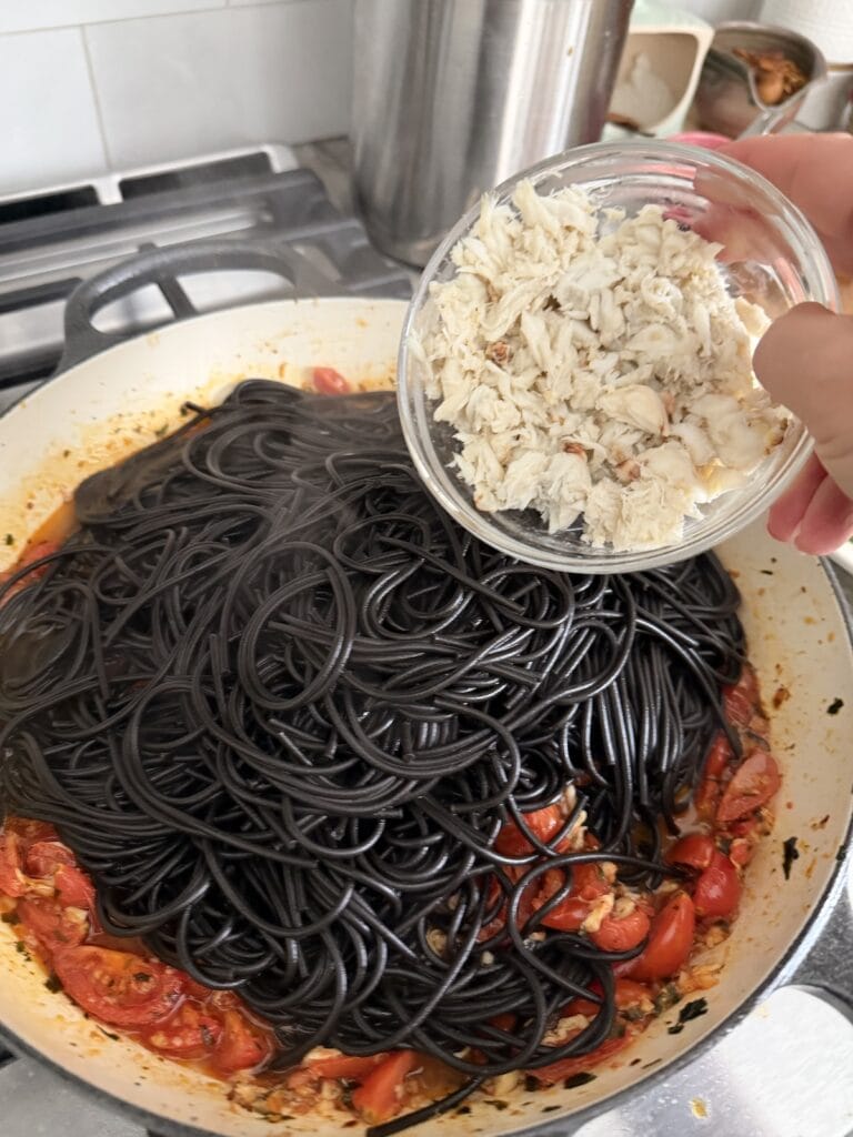 Finishing the Spaghetti Allo Scoglio by adding the spaghetti to sauce along with crabmeant.