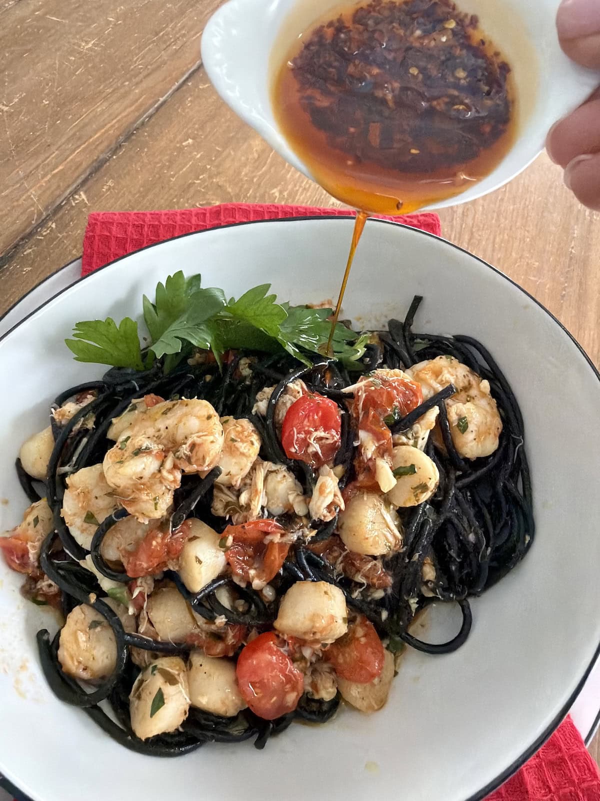 Pouring some olio santo spiacy pepper oil over finished Spaghetti Allo Scoglio.