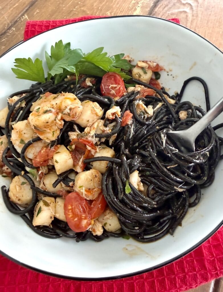 Twirling some Spaghetti Frutti Di Mare with nero di seppia spaghetti n a fork.