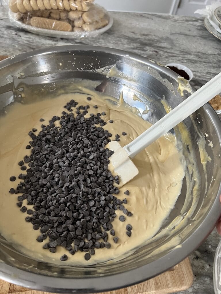 Using a rubber spatula to stir chocolate chips into cream.