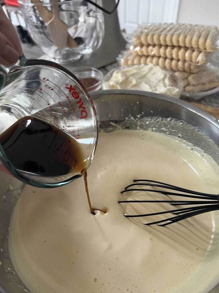 Pouring coffee liqueur mixture into zabaglione.