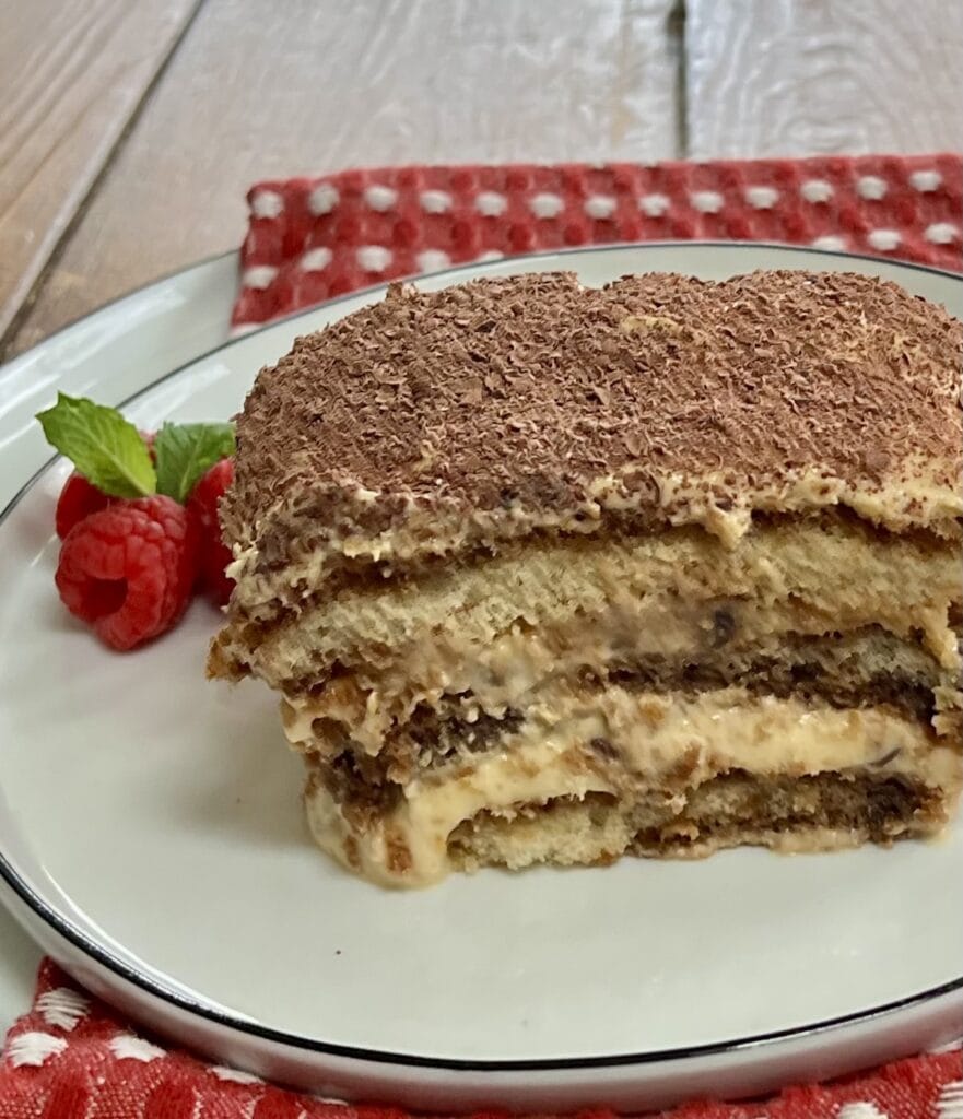 A slice of Authentic Italian Tiramisu Recipe with raspberry garnish on dessert plate.