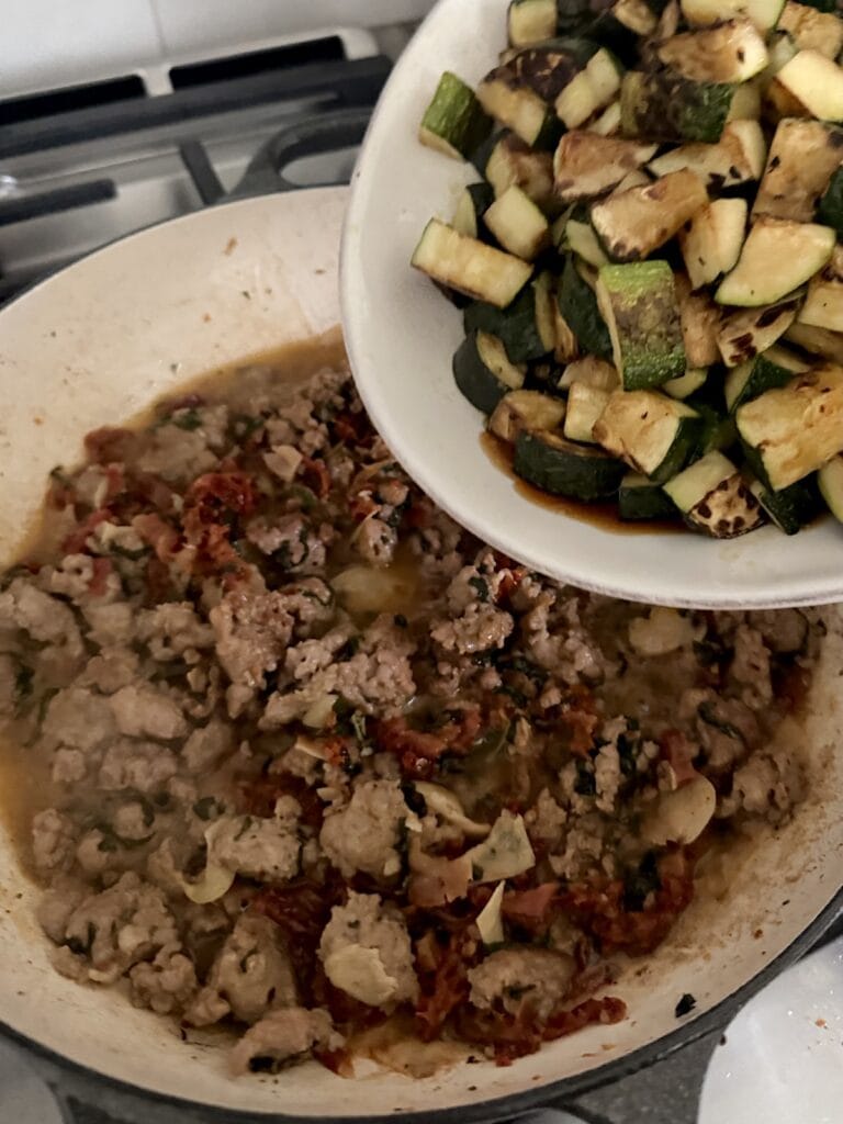 Retruning cooked zucchini back to pan for Pasta with Sausage and Zucchini.