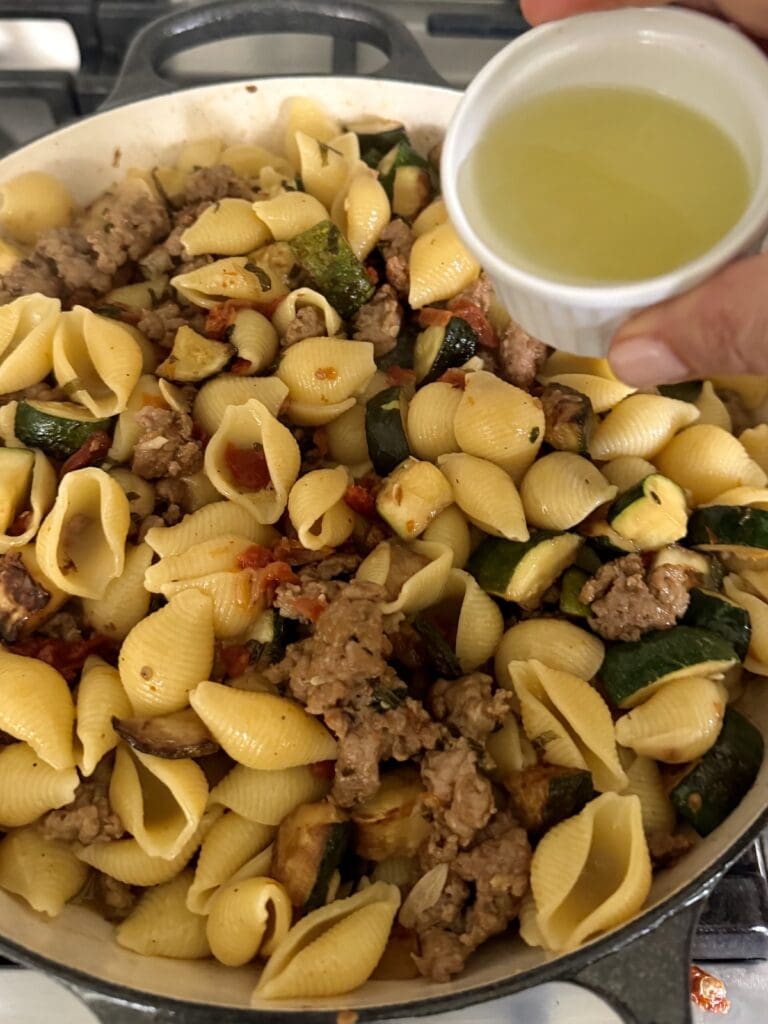 Pouring fresh leon juice into Zucchini and Sausage Pasta