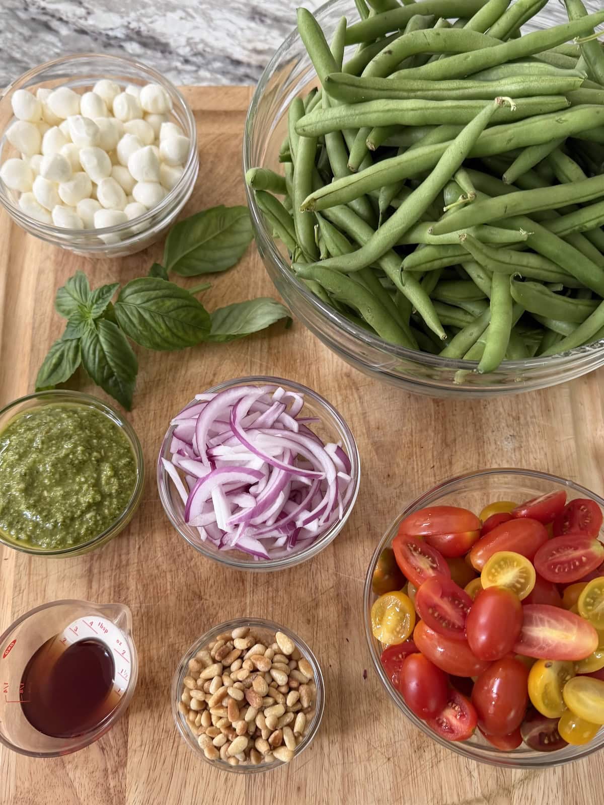 All prepped ingredients for Cold Green Bean Salad on cutting board.