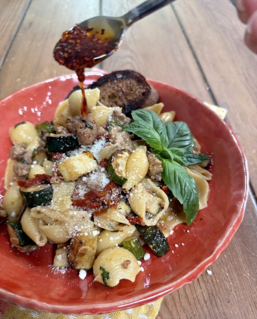 Drizzling some spicy pepper oil over a bowlful of Italian Sausage and Zucchini Pasta.