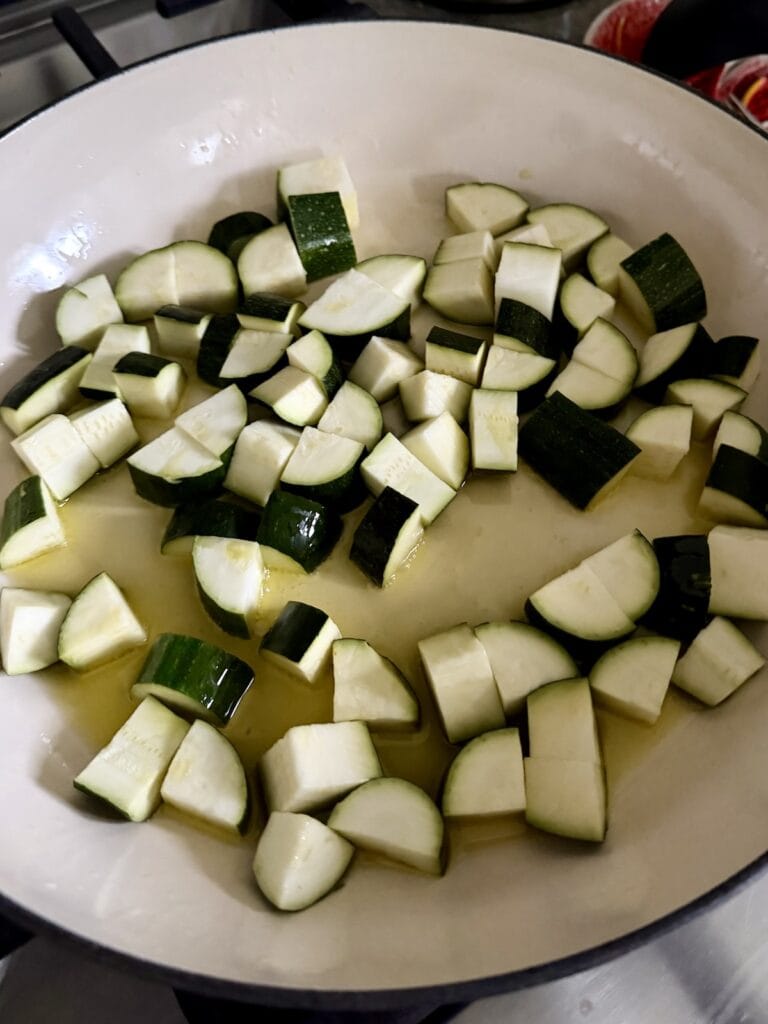 Browning zucchini in hot oil in pan.