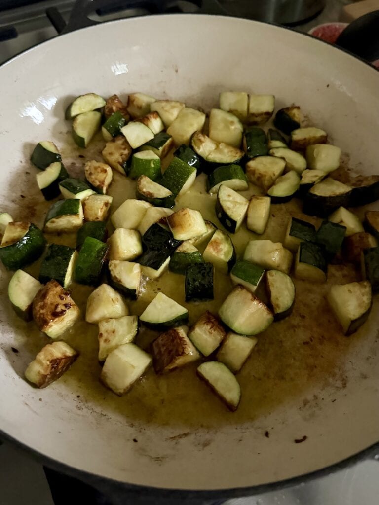 Browning zucchini in hot oil in pan.