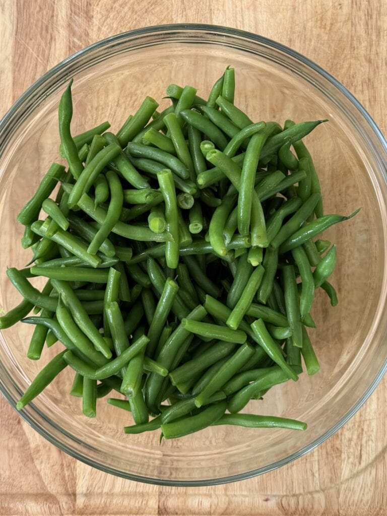 Blanched string beans in bowl ready to be mixed with other ingredients.