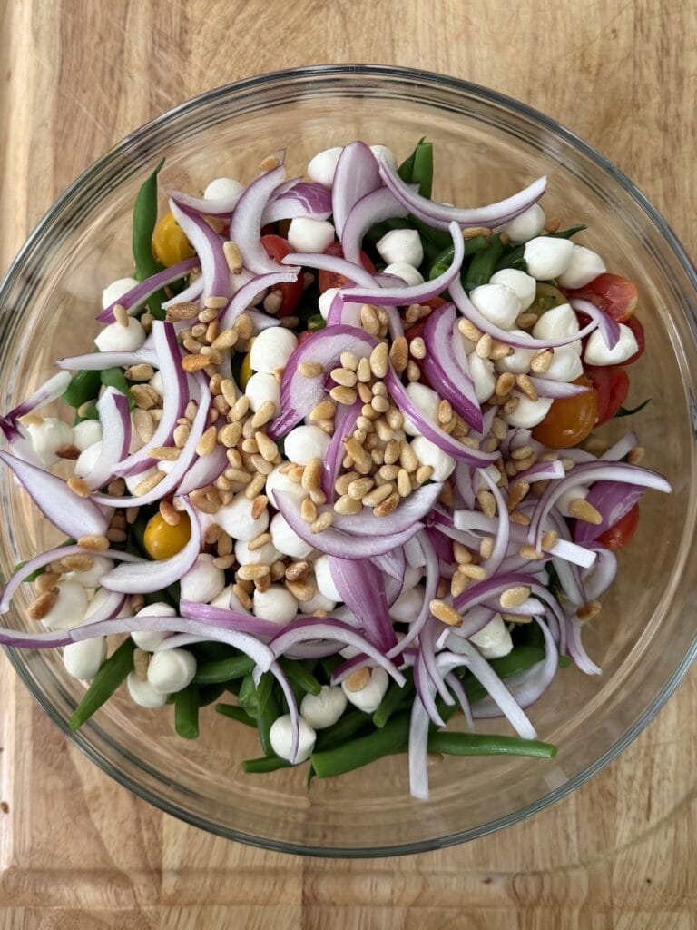 Building the cold string bean salad in glass bowl.