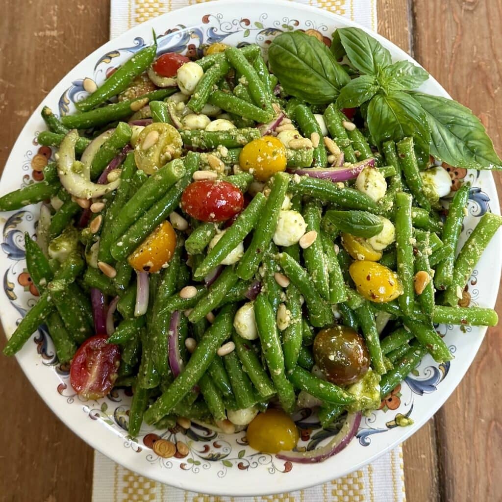 Italian string bean salad with tomatoes and pesto in decorative bowl.