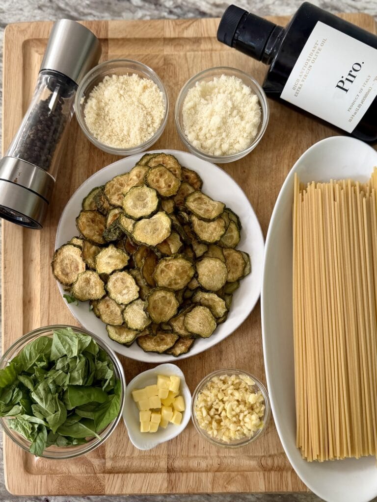 All prepped ingredients for spaghetti alla nerano recipe, including the already fried and rested zucchini slices,  on cuting board.