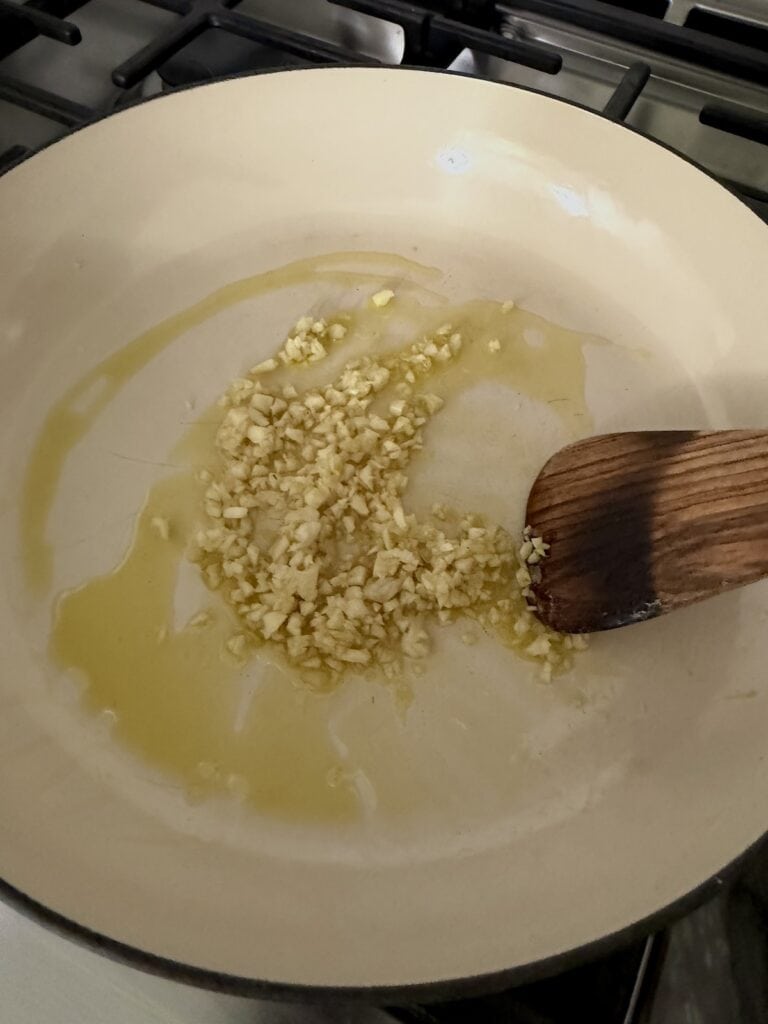 Saut&eacute;ing garlic in olive oil in pan.