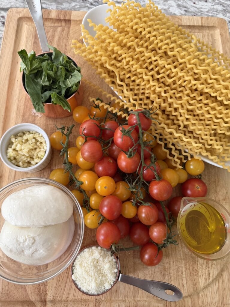 Prepped ingredients for Burst Cherry Tomato Pasta with Burrata on cutting board.