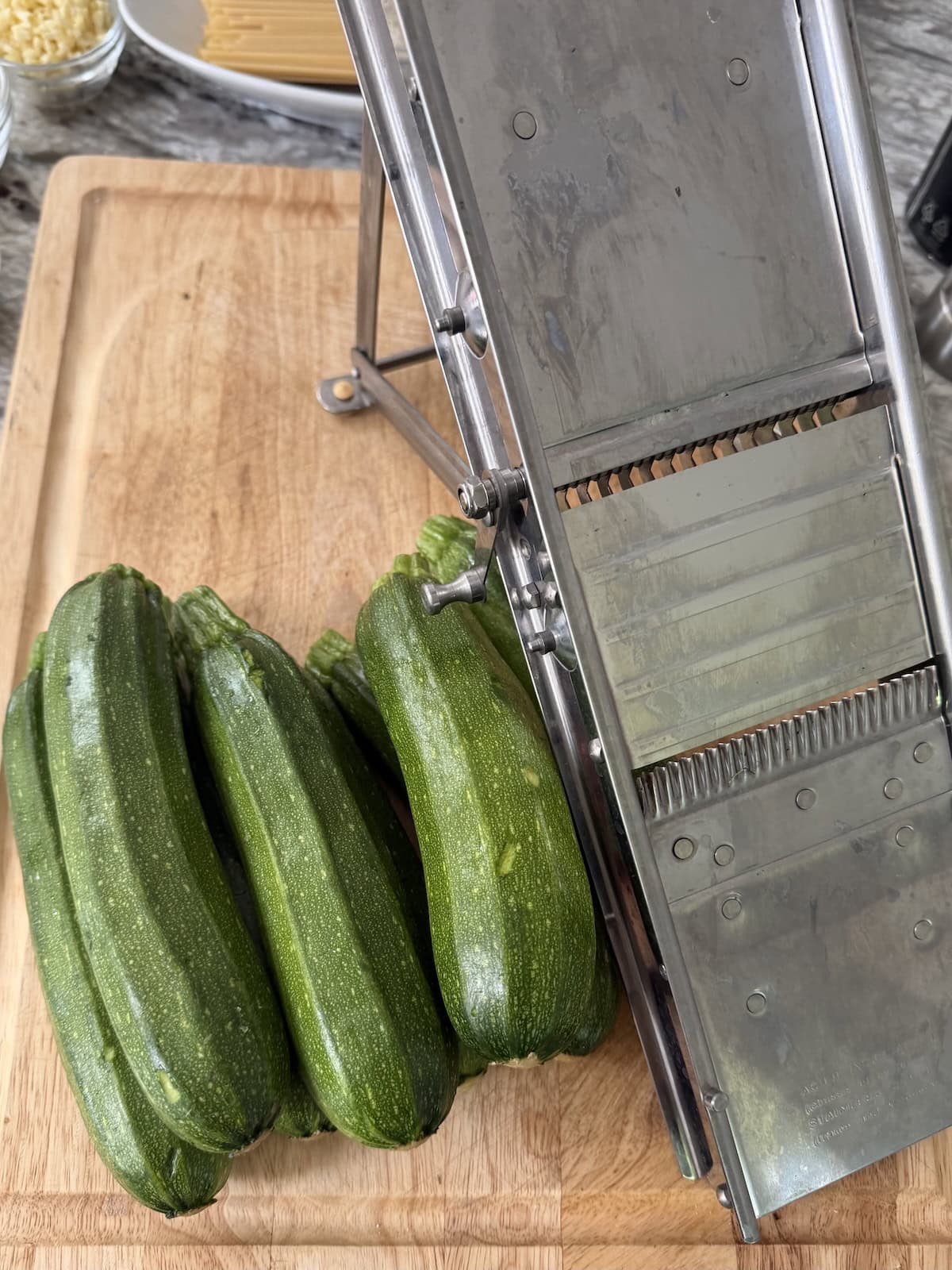 Zucchini and mandoline on cutting board.