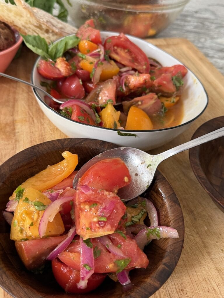 Spooning some italian tomato salad into individual serving bowl.