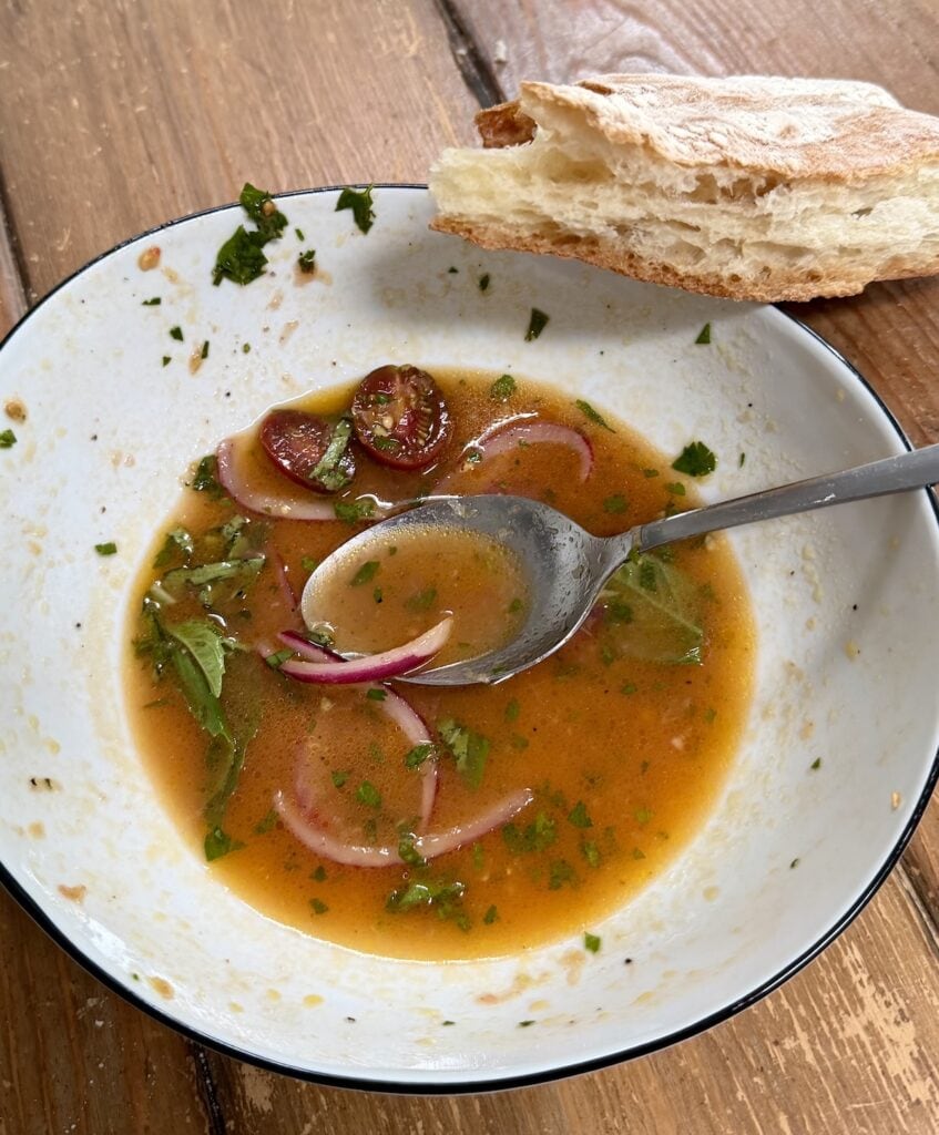 Bowl with remaining dressing and a hunk of bread.