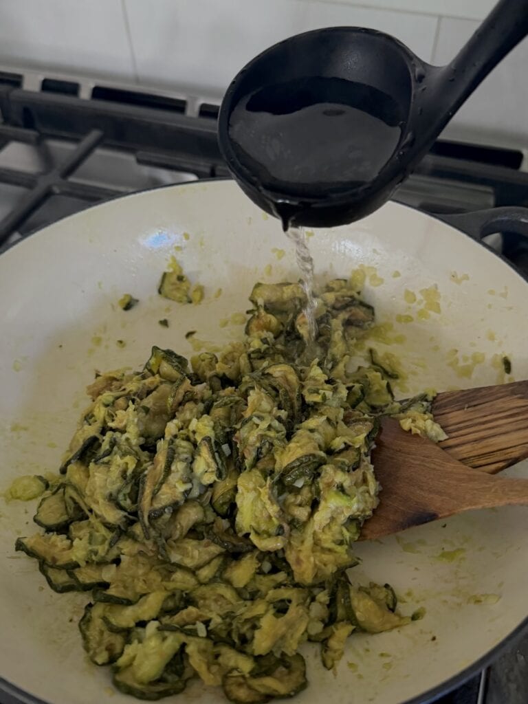 Adding pasta water to pan to help with breaking up the vegetables.