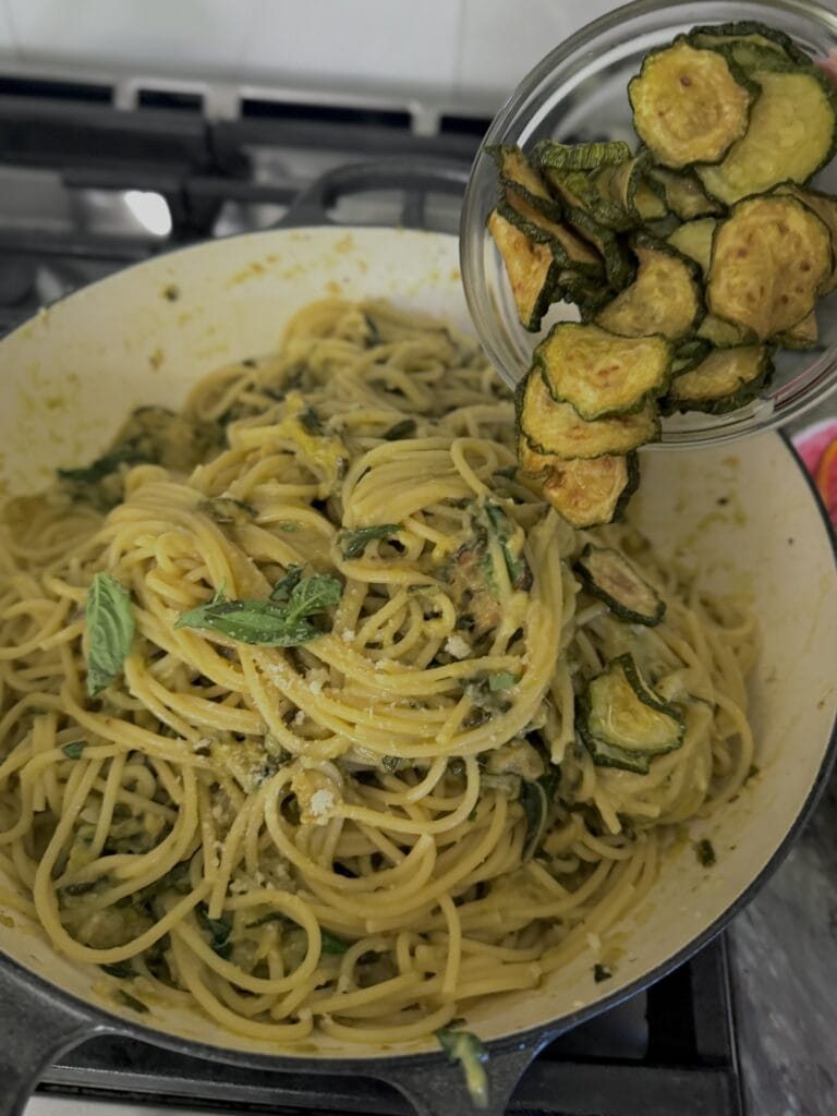 Adding back the reserved fried zucchini slices to the cooked pasta and sauce.