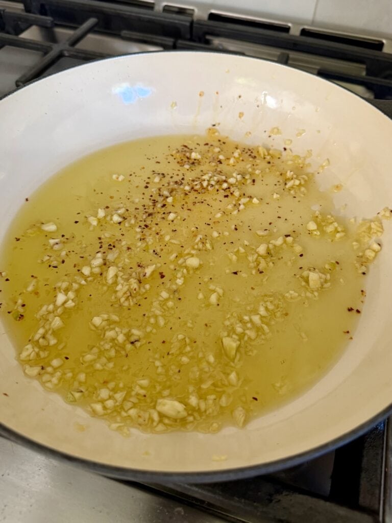Cooking garlic in oil in pan.