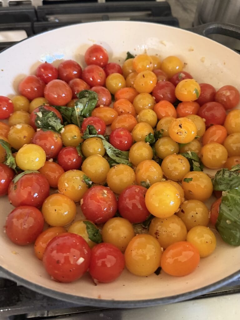 Cherry tomatoes cooking in pan.