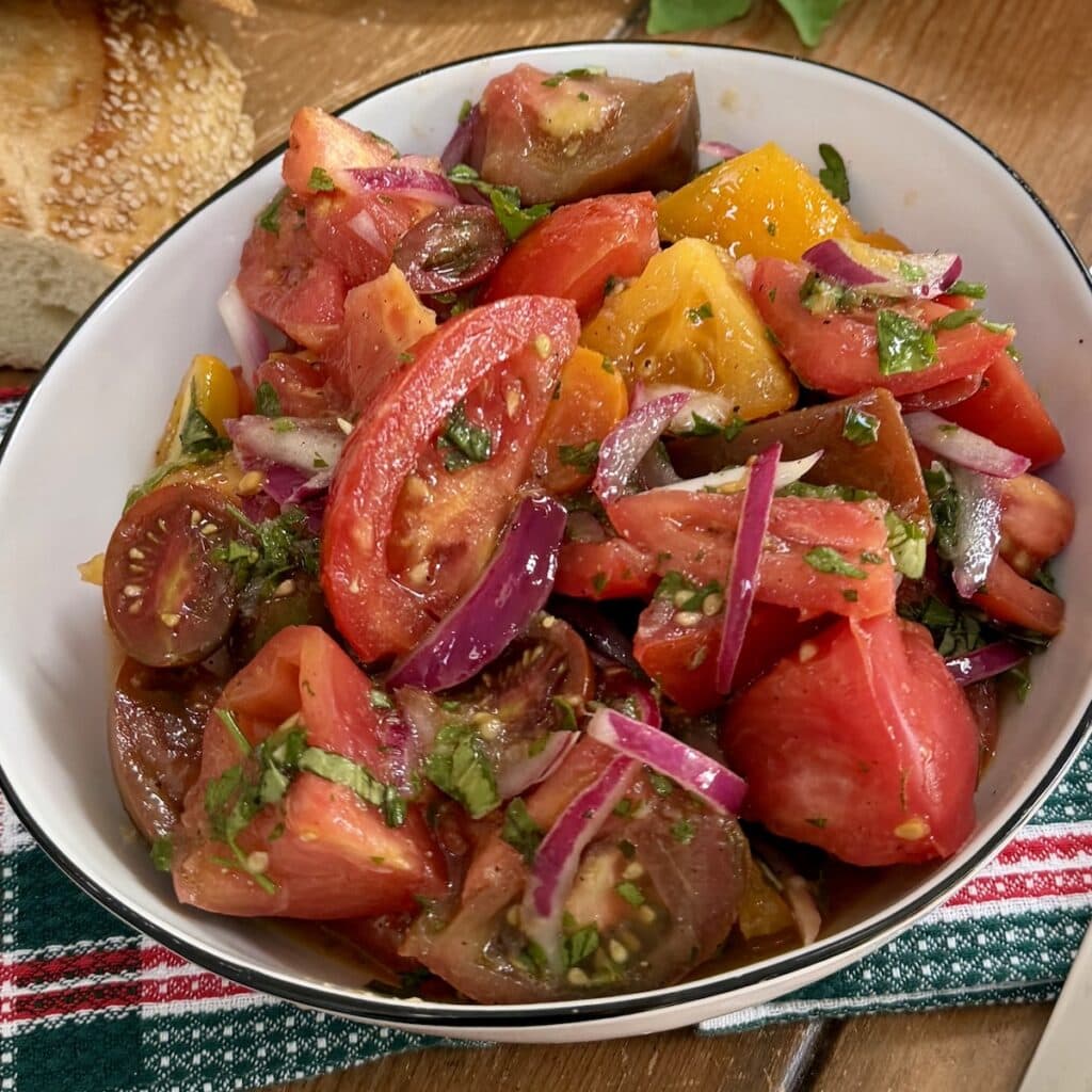 Bowl of Italian Marinated Tomatoes with bread in background.