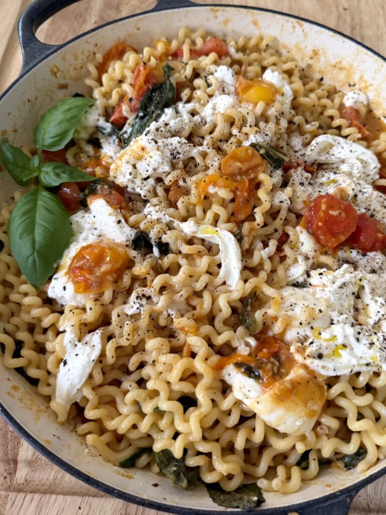 Burst Cherry Tomato Pasta with Burrata and basil garnish in pan.