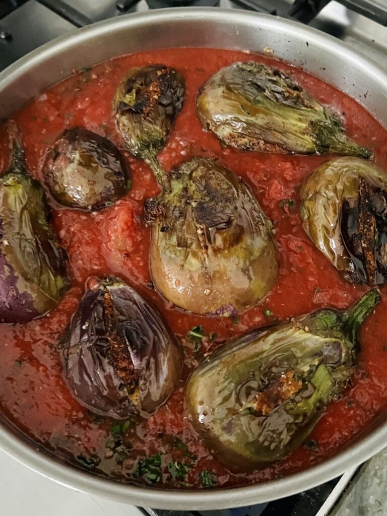 Simmering Sicilian stuffed eggplant in tomato sauce.