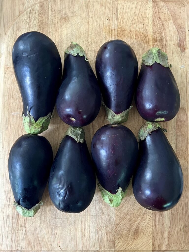 Eight Italian eggplant on cutting board.