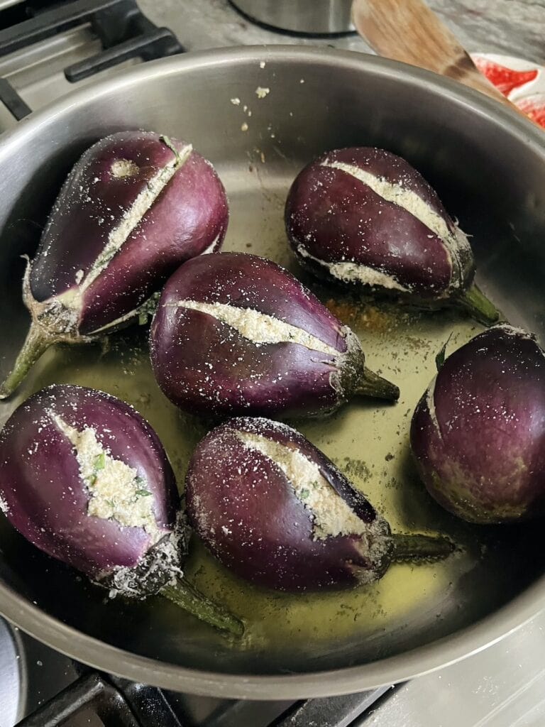 Searing Sicilian stuffed eggplant in deep pan.