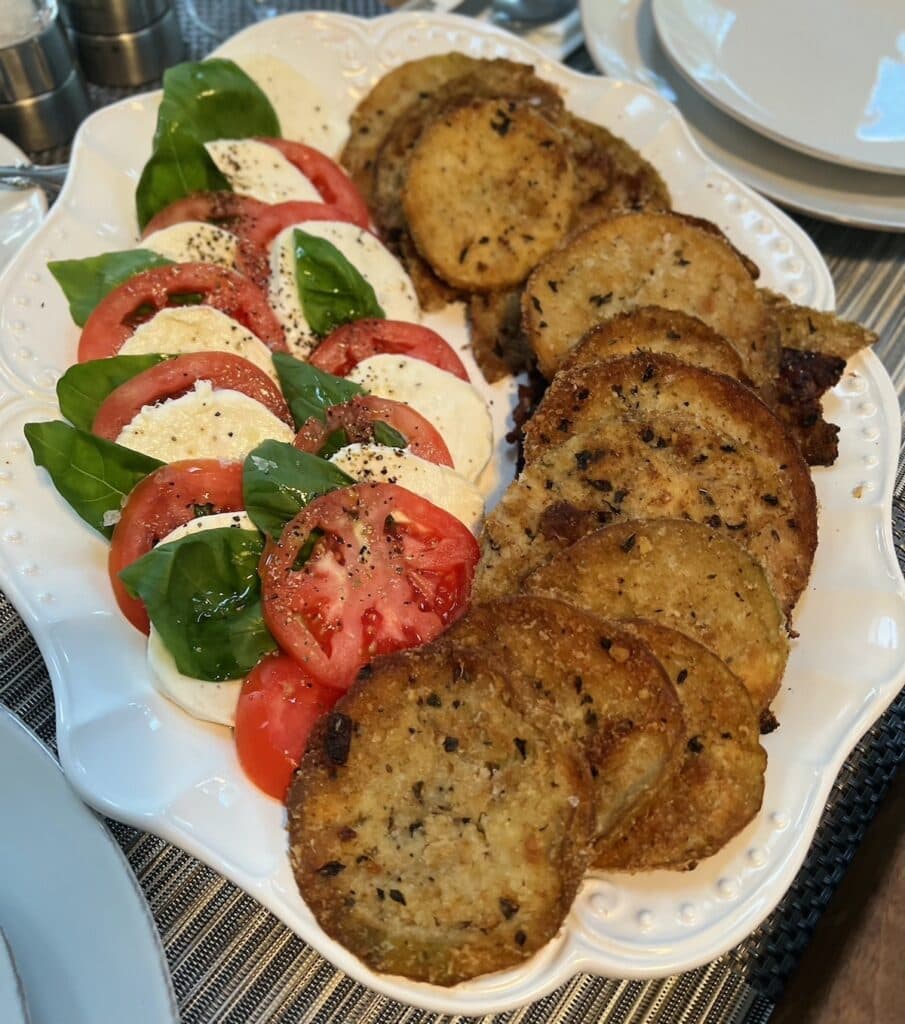 Caprese salad with fried eggplant slices on white platter.
