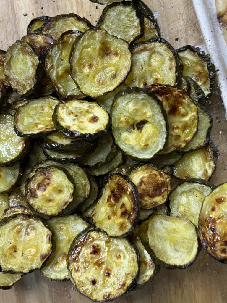 Roasted thin zucchini slices on cutting board.