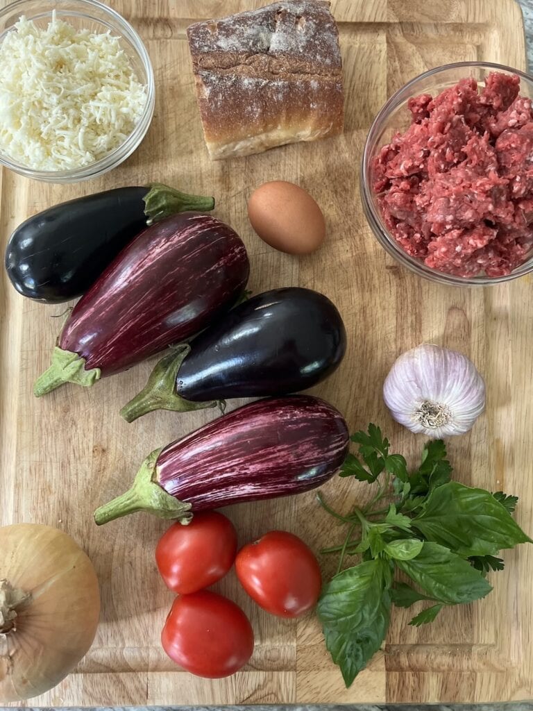 All ingredients for beef and cheese stuffed eggplant on cutting board.