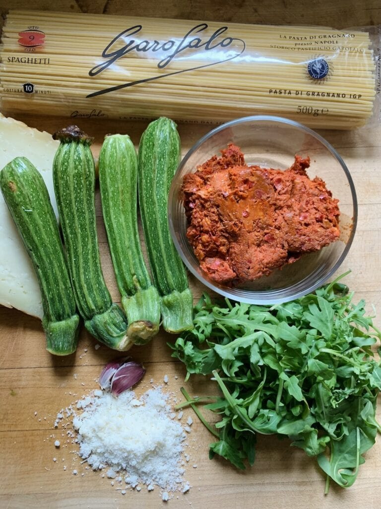 All ingredients for Zucchini pasta with 'nduja and arugula on cutting board.