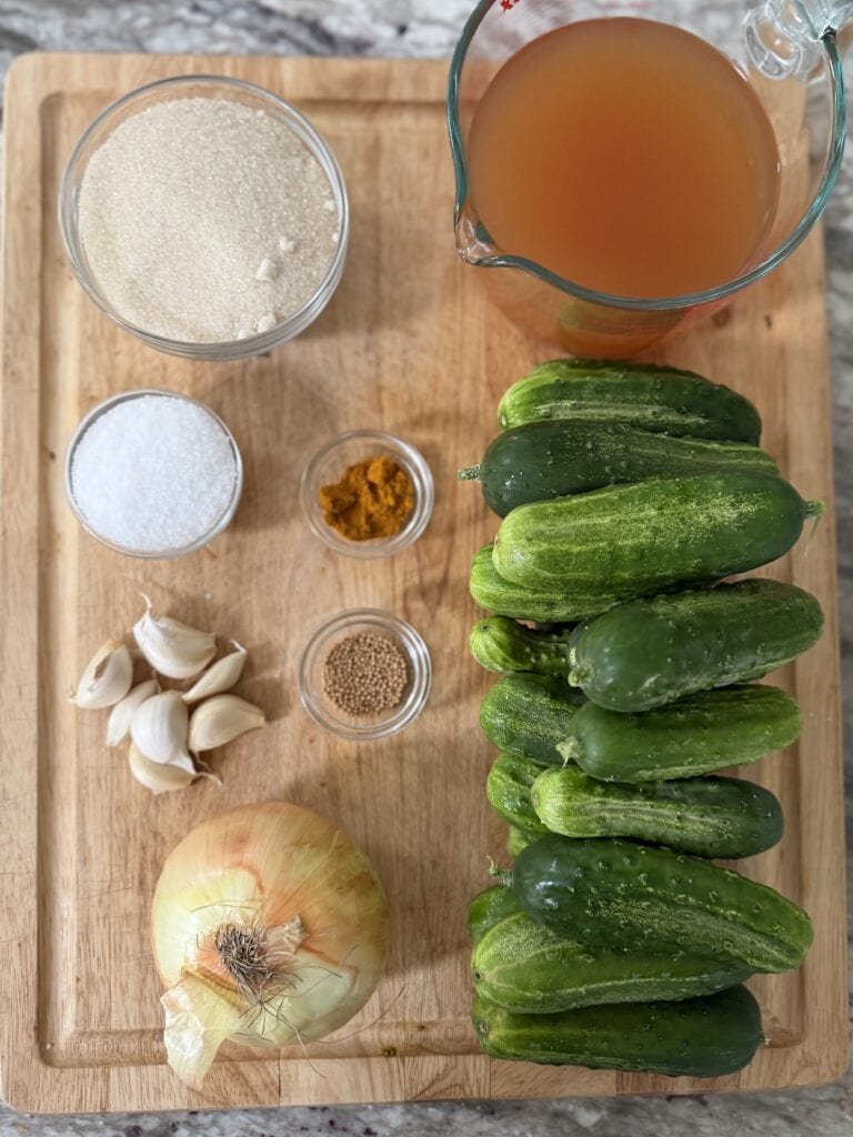All ingredients for refrigerator bread and butter pickles on cutting board.
