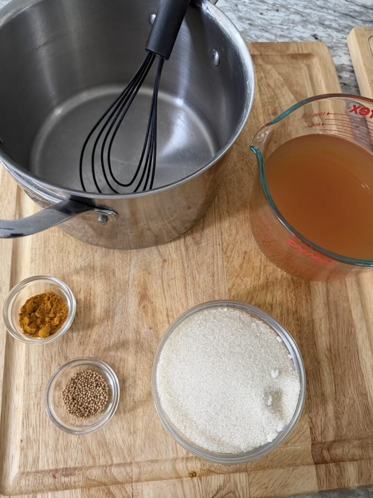 The brine ingredients and a pot with whisk on cutting board.