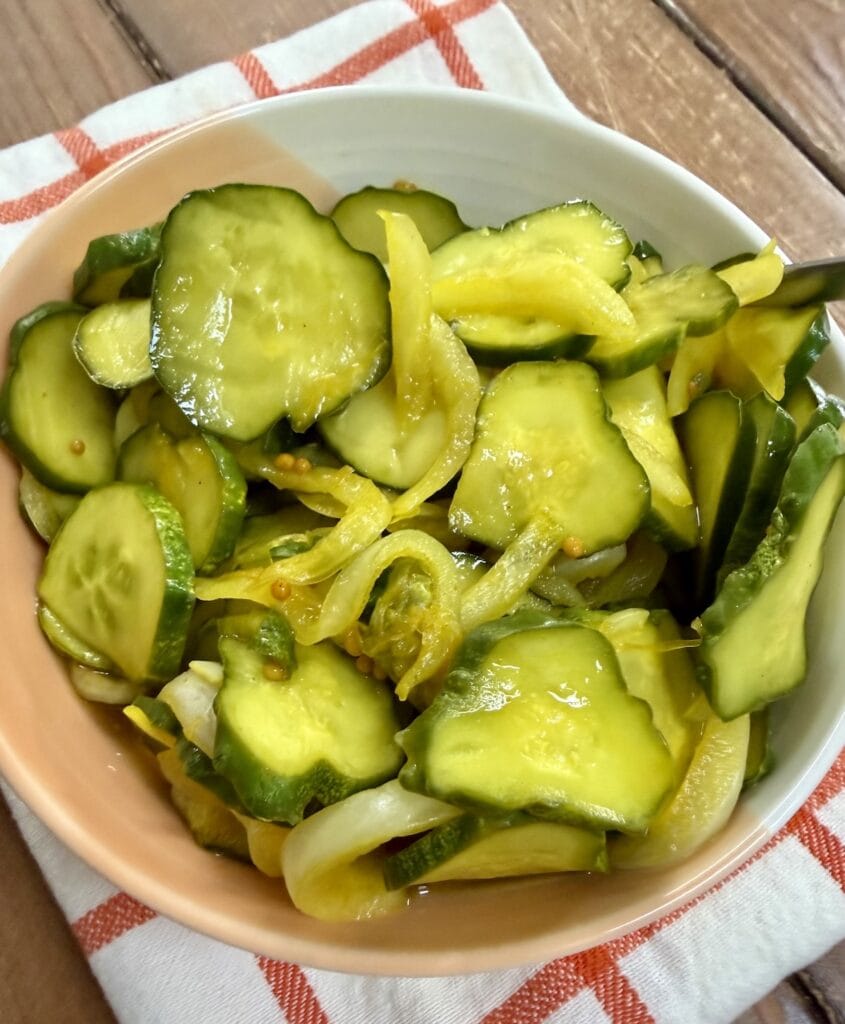No canning easy bread and butter pickles in bowl over decorative towel.