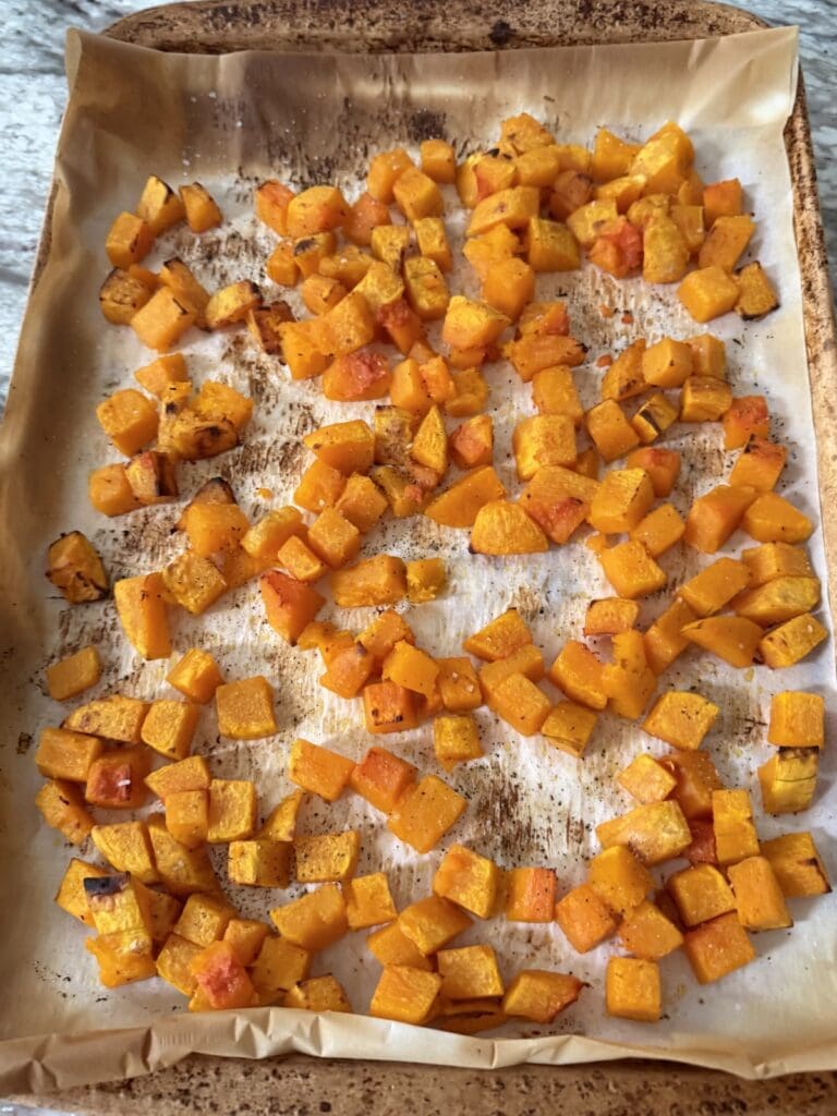 The finished, roasted diced butternut squash on roasting pan.