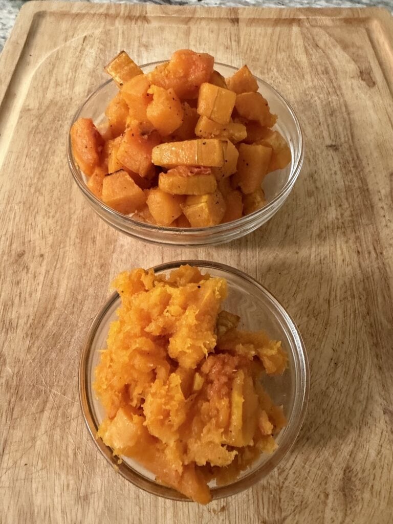 The finished roasted butternut cubes and mashed butternut in glass nbowls on cutting board, respectively.