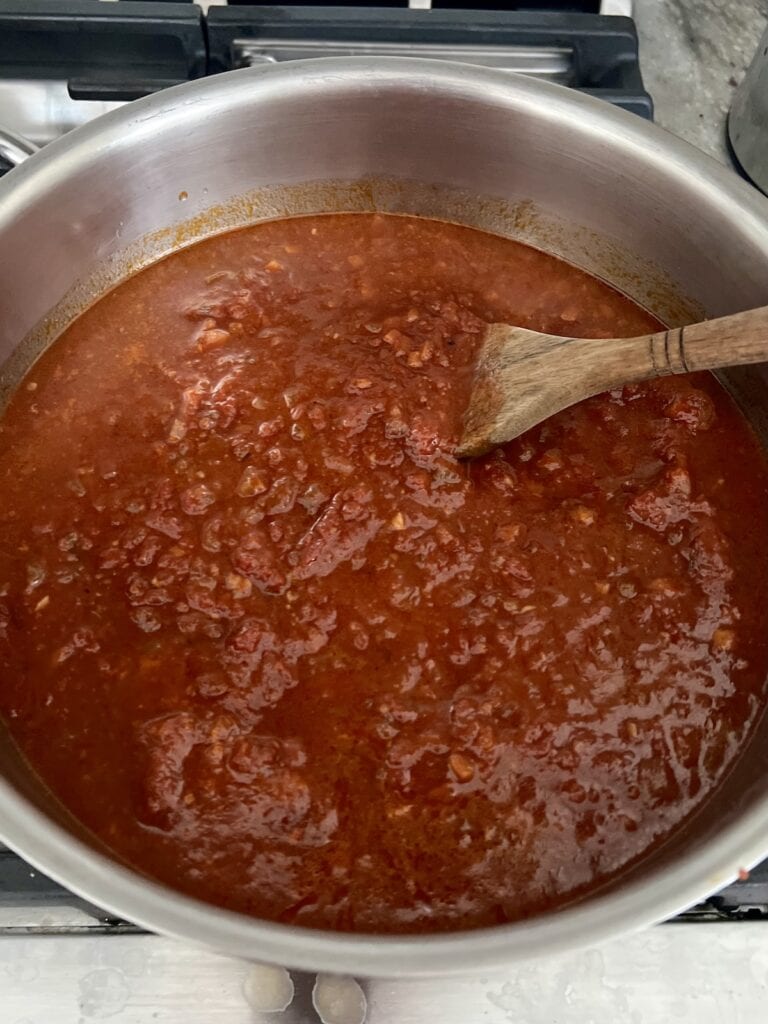 Sauce heating in pot ready to be mixed with cooked pasta.