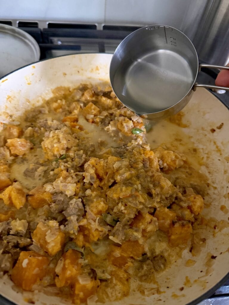 Adding some pasta water to sauce to thin it out.