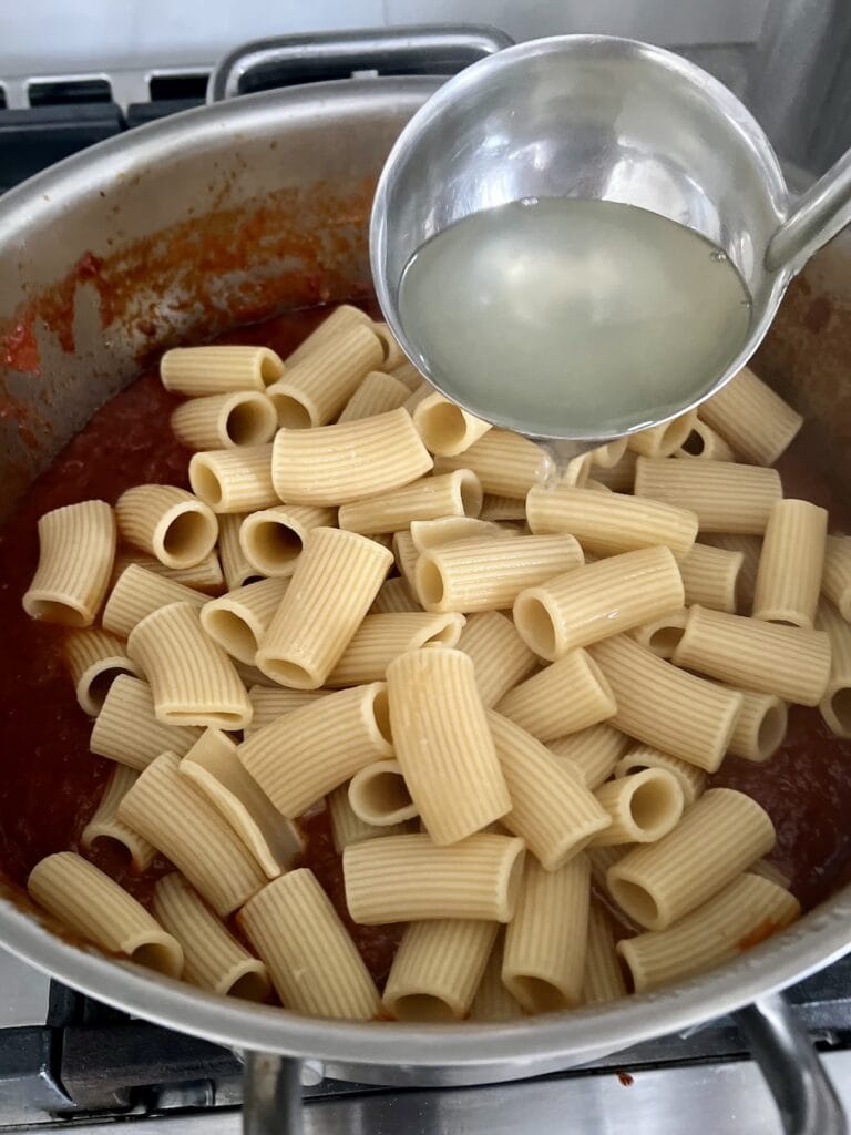 Adding pasta water to pot of sunday sauce and gravy.